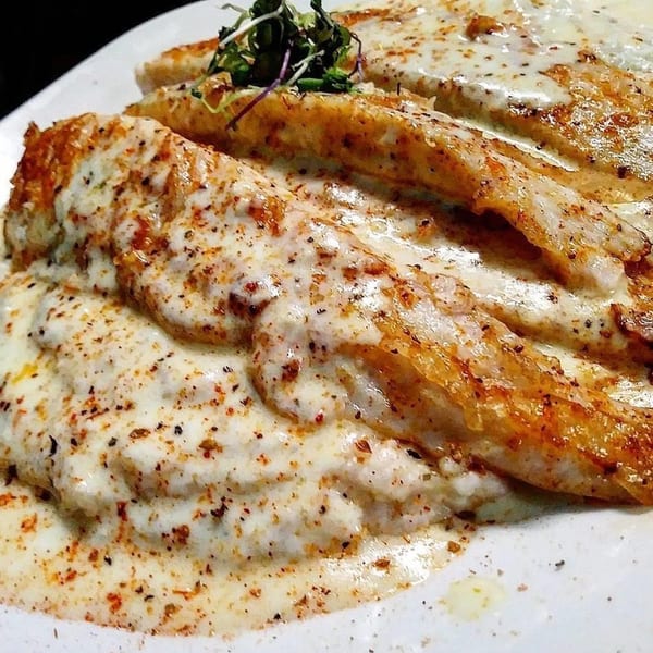 Chef Reeky's Cafe & Juice Bar's soul food dish of seasoned fish fillets covered in creamy white sauce.