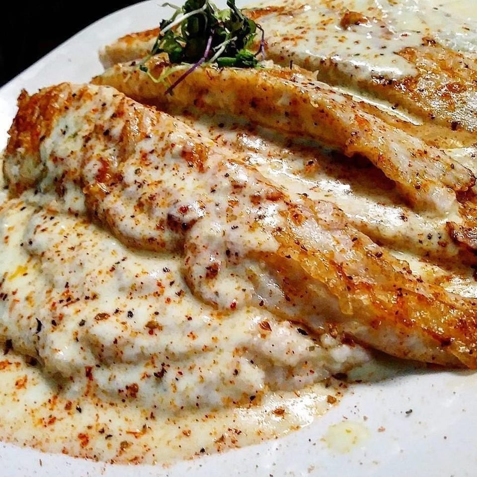 Chef Reeky's Cafe & Juice Bar's soul food dish of seasoned fish fillets covered in creamy white sauce.
